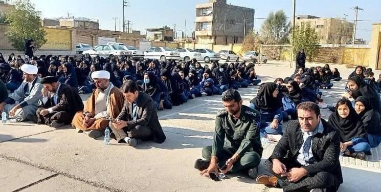 نشاندن مسئولان شهر و دانش آموزان کف آسفالت توسط امام جمعه